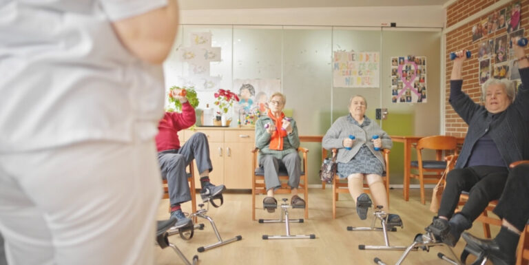 Elderly Residents Doing Chair Exercises with Dumbbells at an Assisted Living Facility