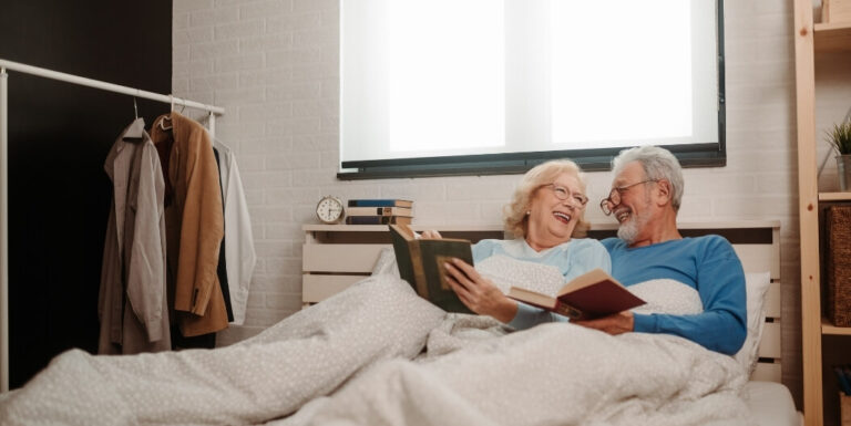 Elderly Couple Reading Books Together in Bed at Assisted Living Facility